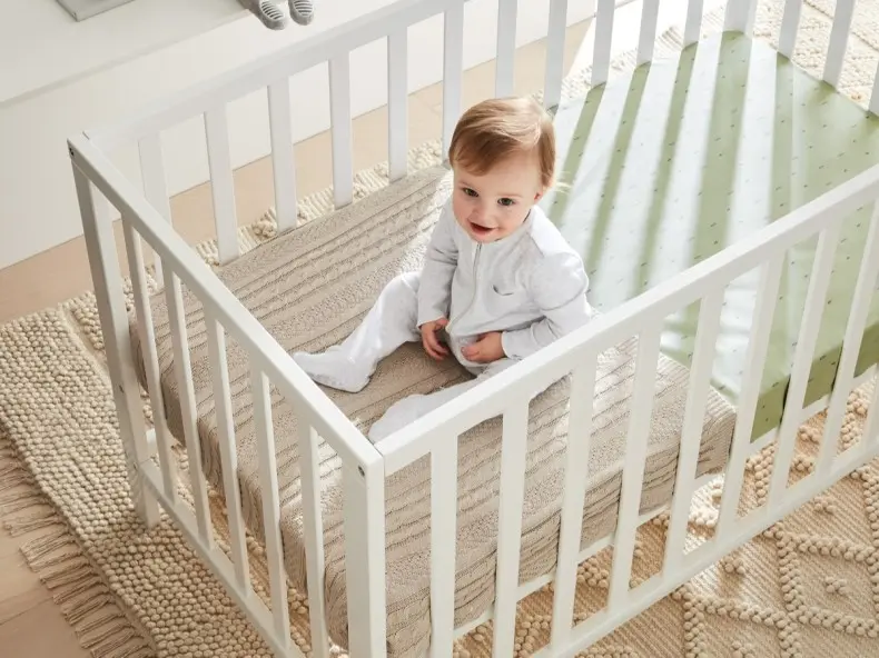 white baby cot with baby smiling