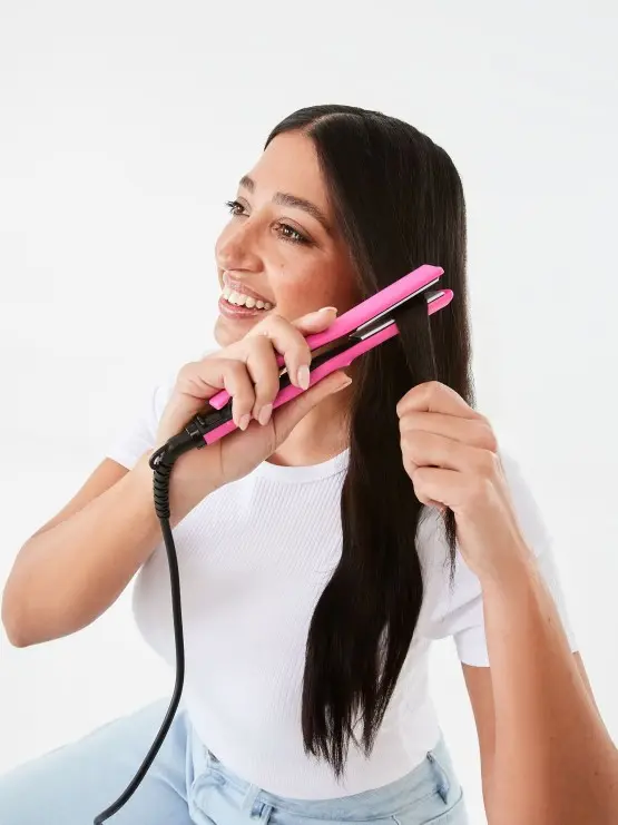 a lady using a Mini Straightener that is Hot Pink co