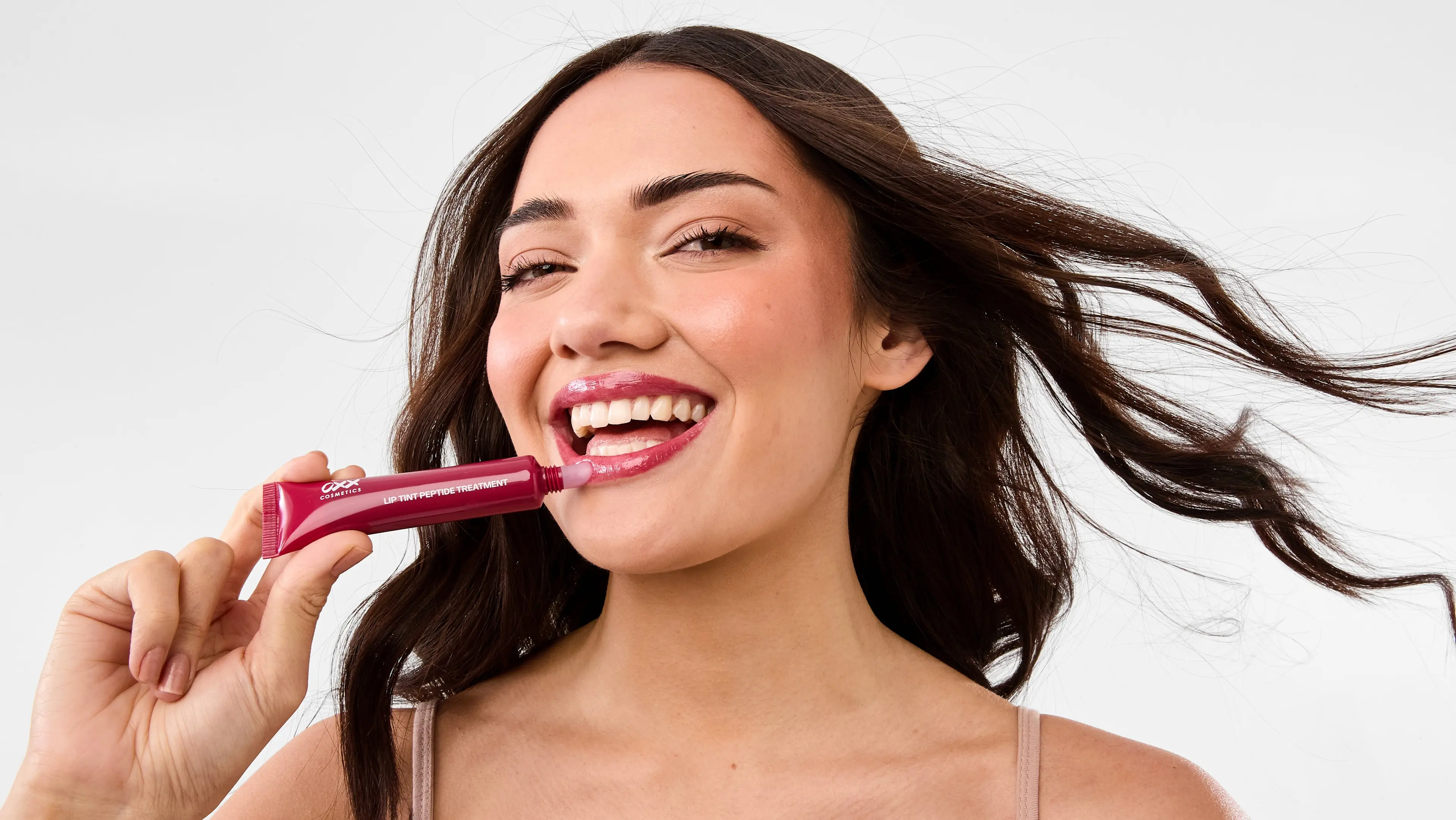 Woman applying the OXX Cosmetics Lip Tint Peptide Treatment