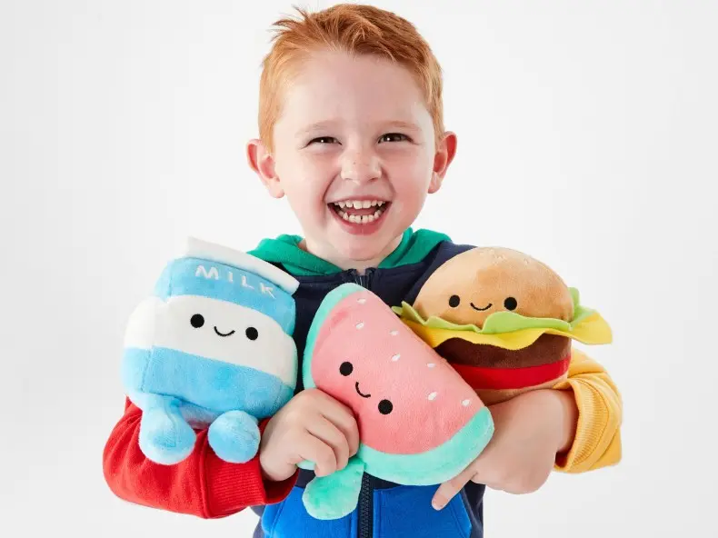 young boy hugging three plush toys