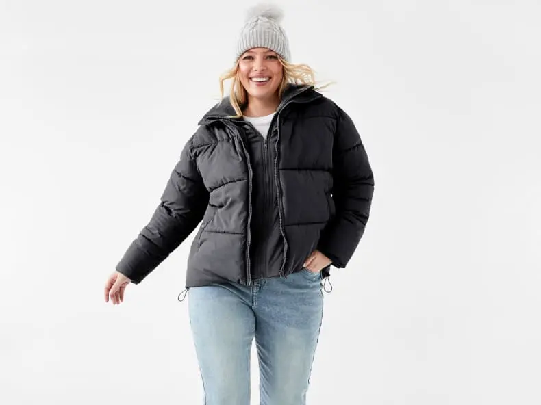 a woman wearing a black puffer jacket and grey be
