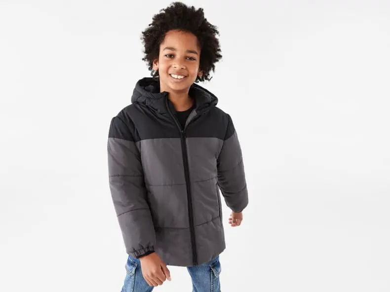young boy wearing a black and grey puffer ja
