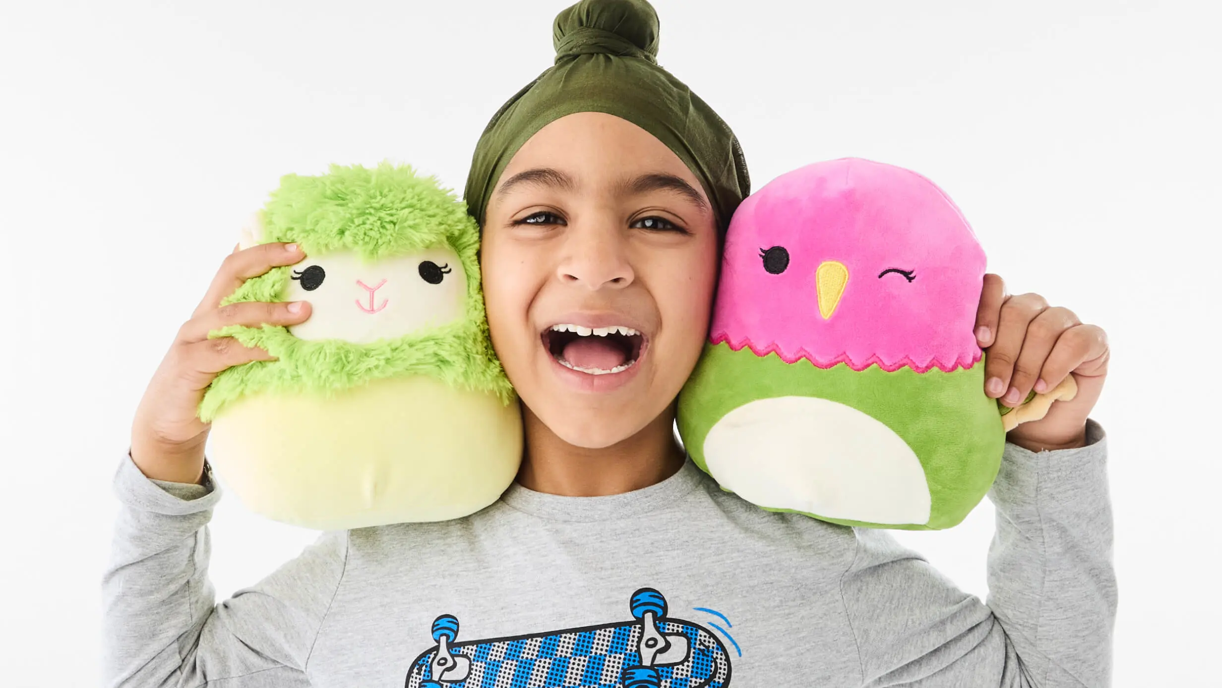 young boy holding two squishmallow toys