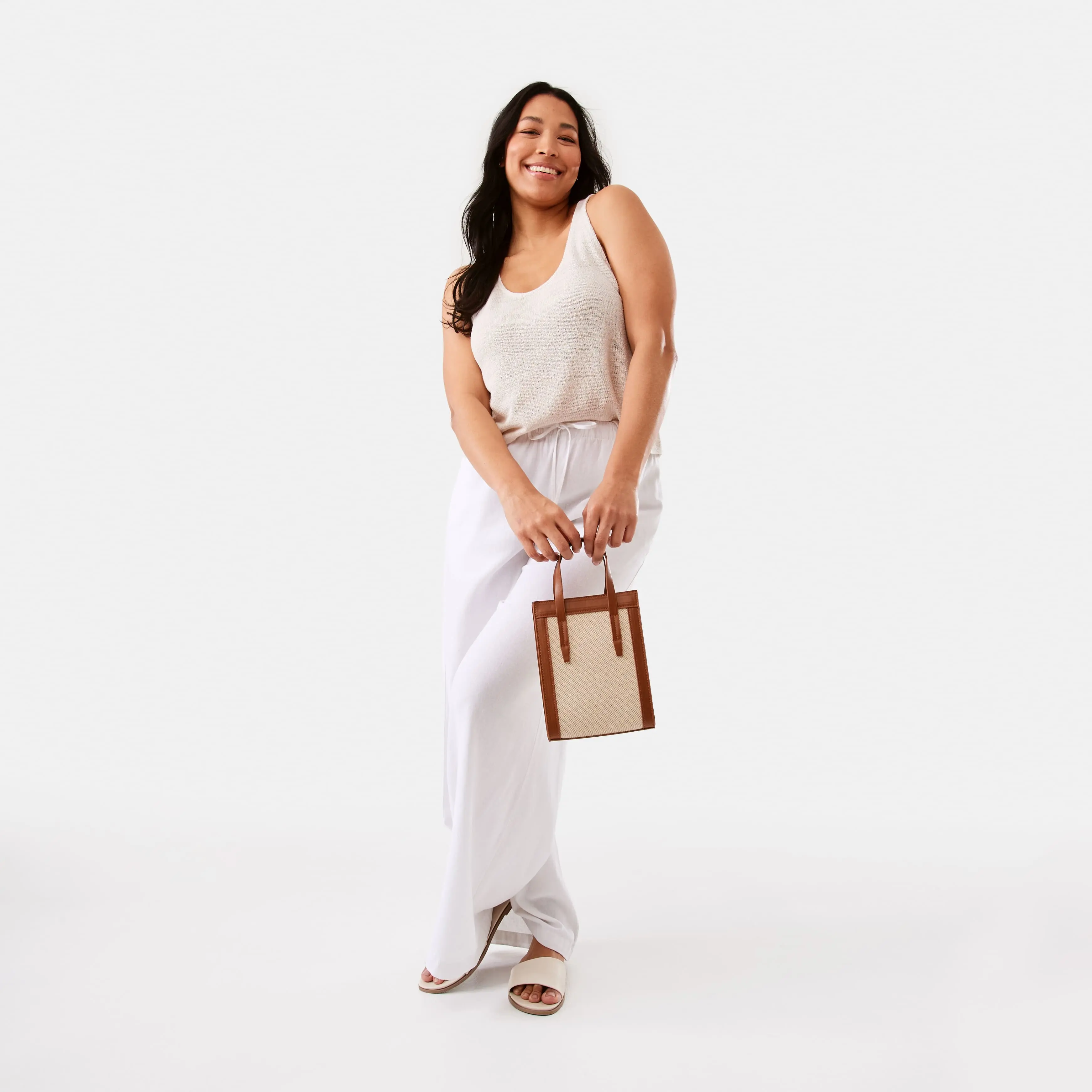 Talent wearing beige linen blend top paired with linen smart pants and carrying handbag