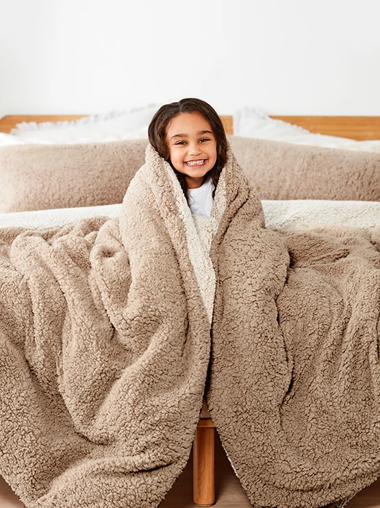 young girl smiling wrapped up in a cozy bla