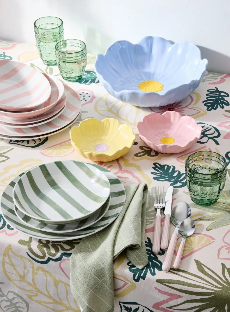 Natural themed dining table set-up with a dinner set, floral bowls, cutlery and drinking glasses