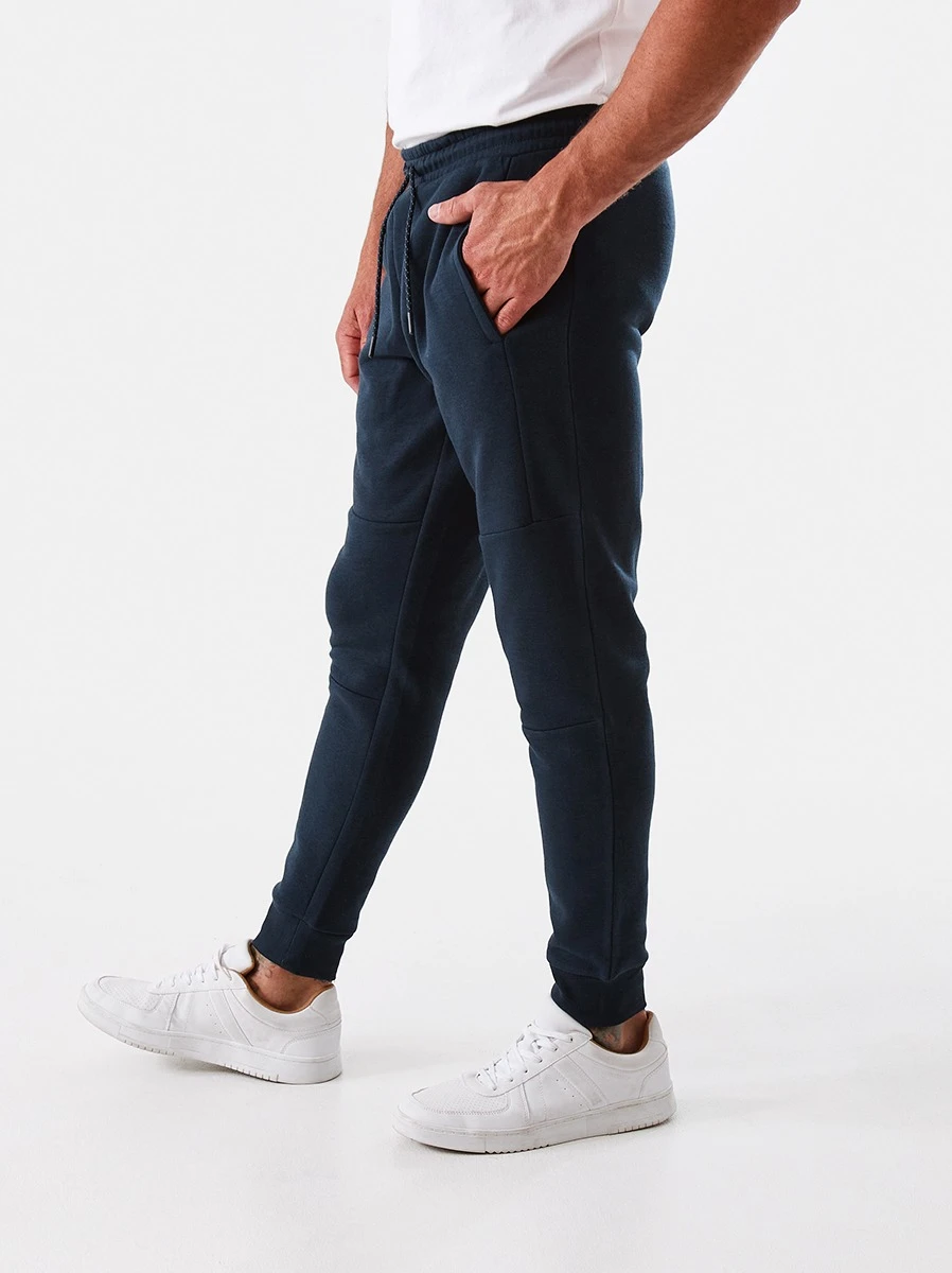 Man wearing blue trackpants and white shoes