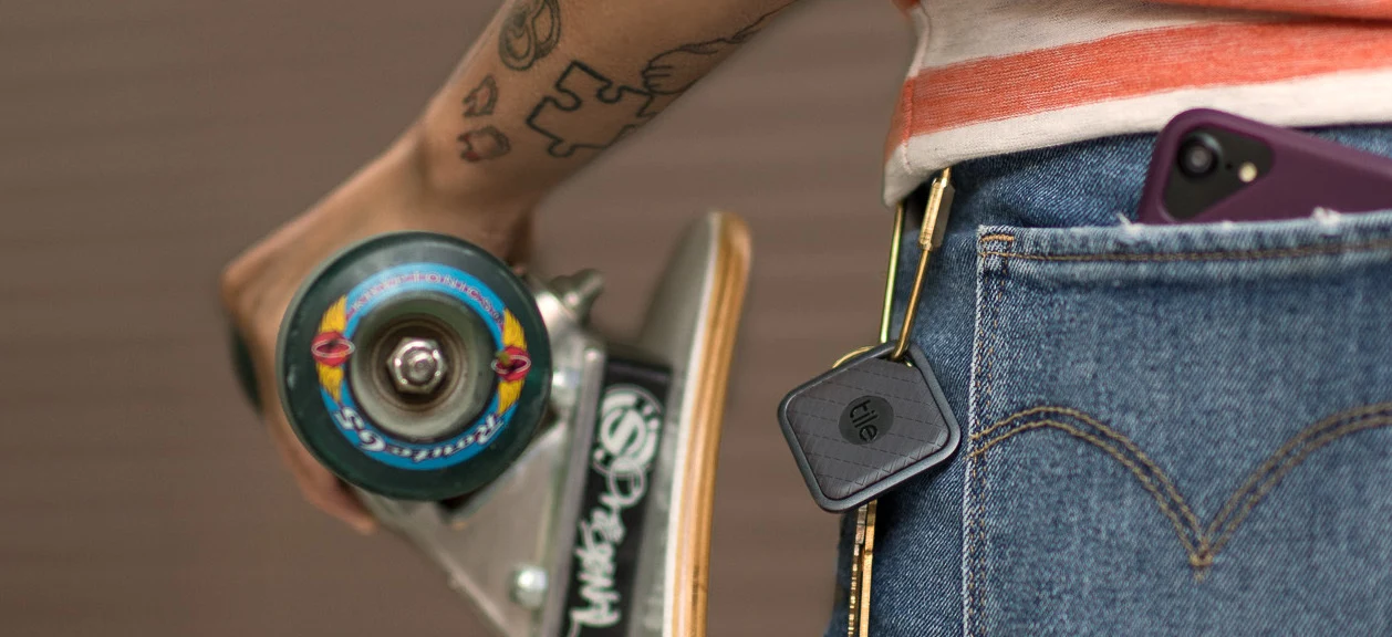 A person with a skateboard and a Tile attached to their keys