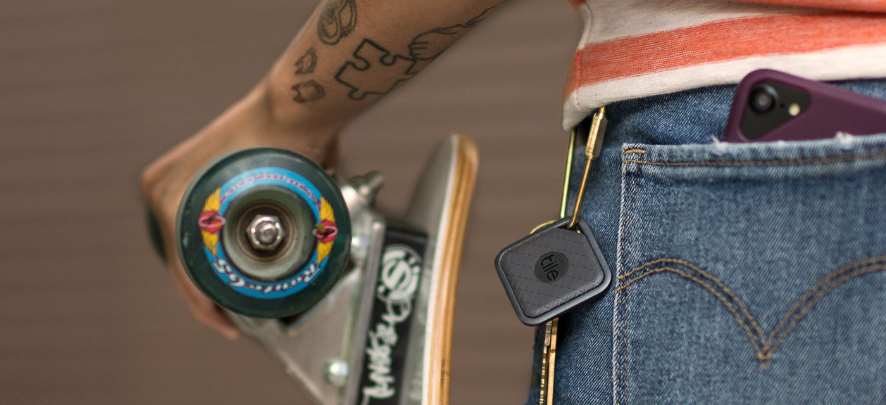A person with a skateboard and a Tile attached to their keys