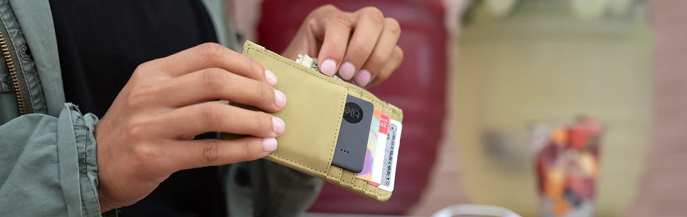 A person with a slim wallet with a Tile slim in the cardholder