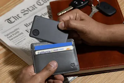 A Life360 Tile Slim Black placed inside a person's wallet.