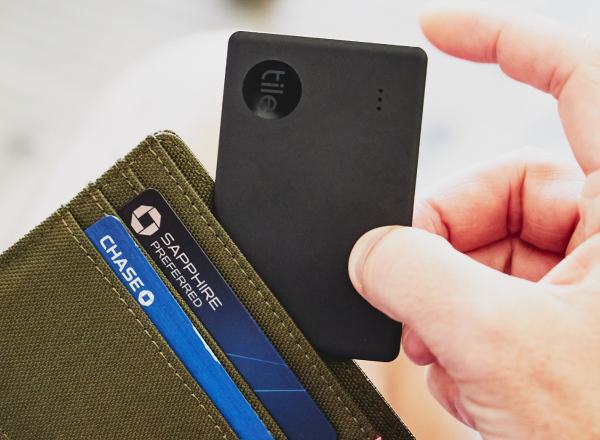 A Black 2022 Tile Slim being placed inside a person's wallet.