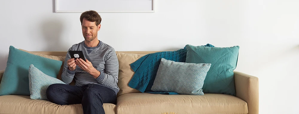 A person sitting on a couch with a Tile on their tablet