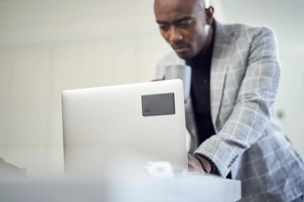 A well-dressed man using his Laptop that has a 2020 Slim adhesively attached to the cover