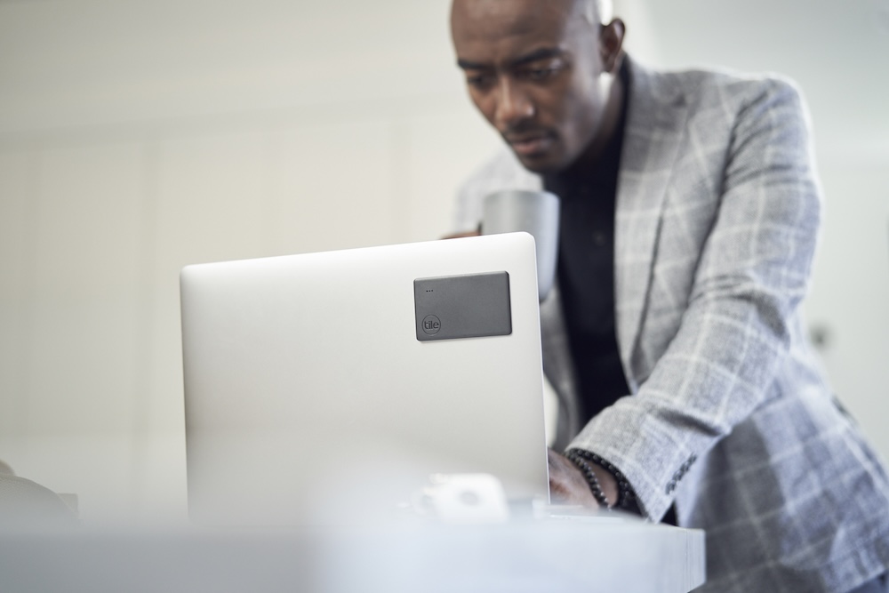 A well-dressed man using his Laptop that has a 2020 Slim adhesively attached to the cover
