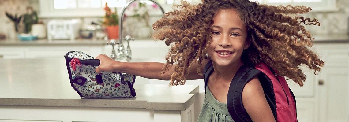 A kid grabbing her lunchbox with a Tile attached