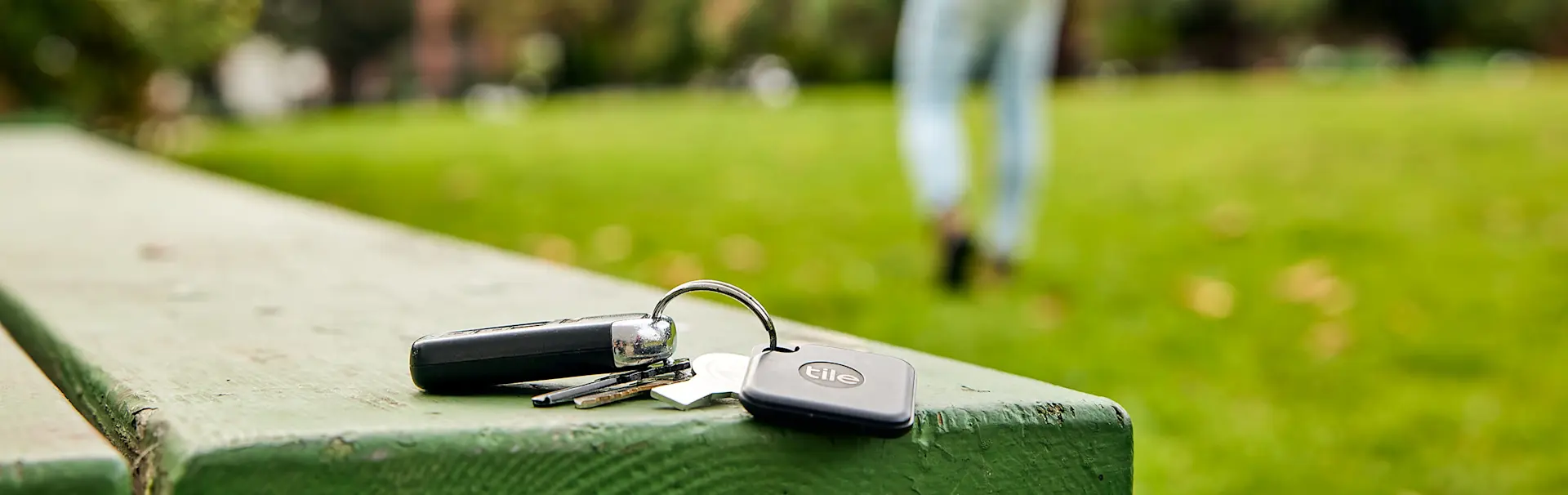 A set of car keys left on a bench with a Tile mate attached