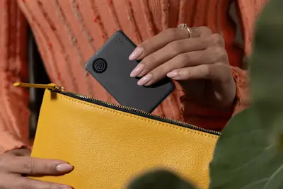A Life360 Tile Slim being placed in a yellow pouch.