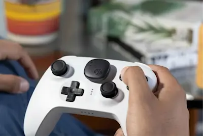 A Life360 Tile Sticker - Black placed on a white wireless controller.
