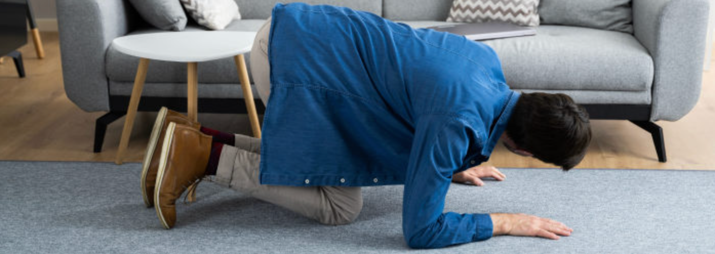 A person looking for something under the couch