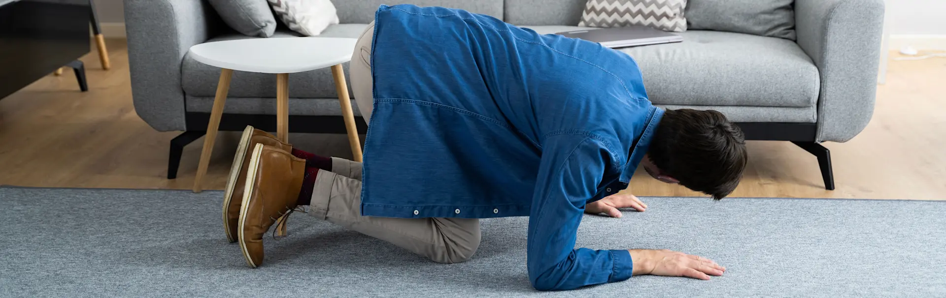 A person looking for something under the couch