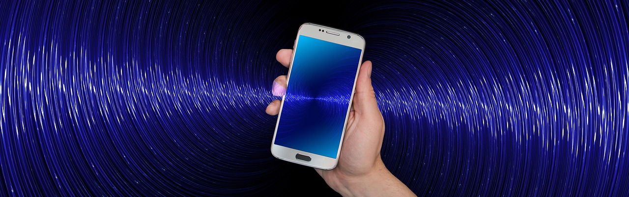 Person holding a smartphone with WiFi waves coming out of it.