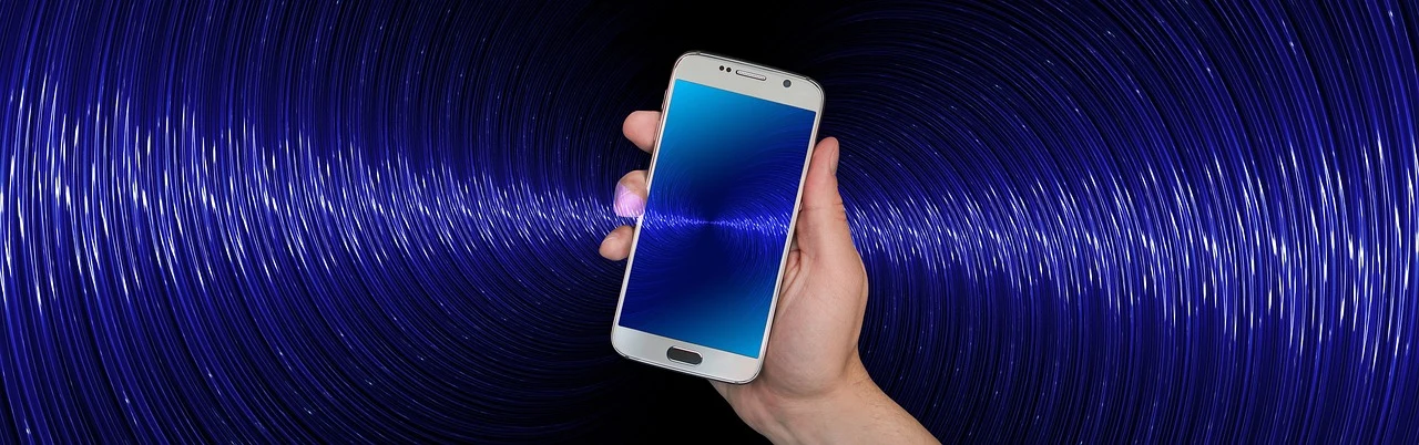 Person holding a smartphone with WiFi waves coming out of it.