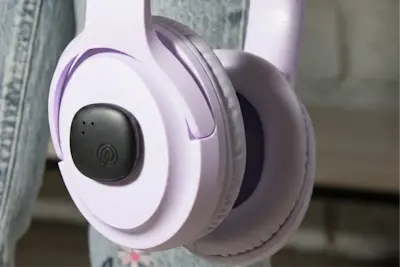 A Life360 Tile Sticker - Black placed on purple headphones 