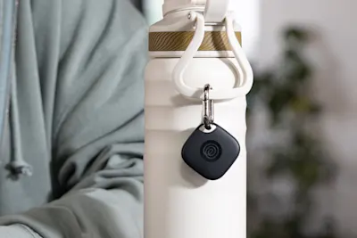 A Life360 Tile attached to a white water bottle. 