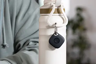 A Life360 Tile attached to a white water bottle.