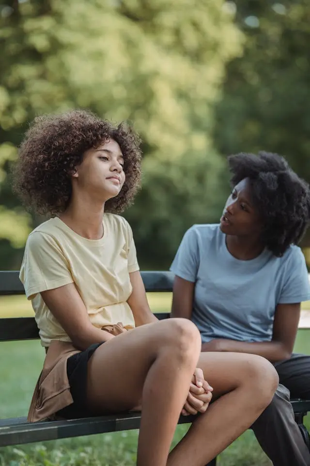 Black mother speaking firmly to her daughter who avoids eye contact. 
