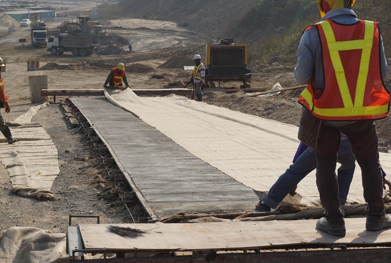 Worker_laying_burlap_on_concrete_pavement_surface_for_curing_work