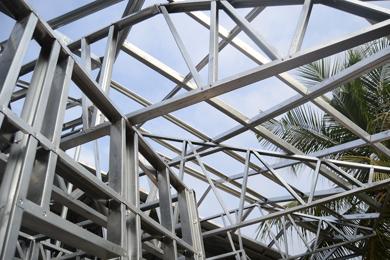 close-up_of_a_steel_roof_truss_system_with_cross_bracing_and_supports_against_a_background_of_clear_skies