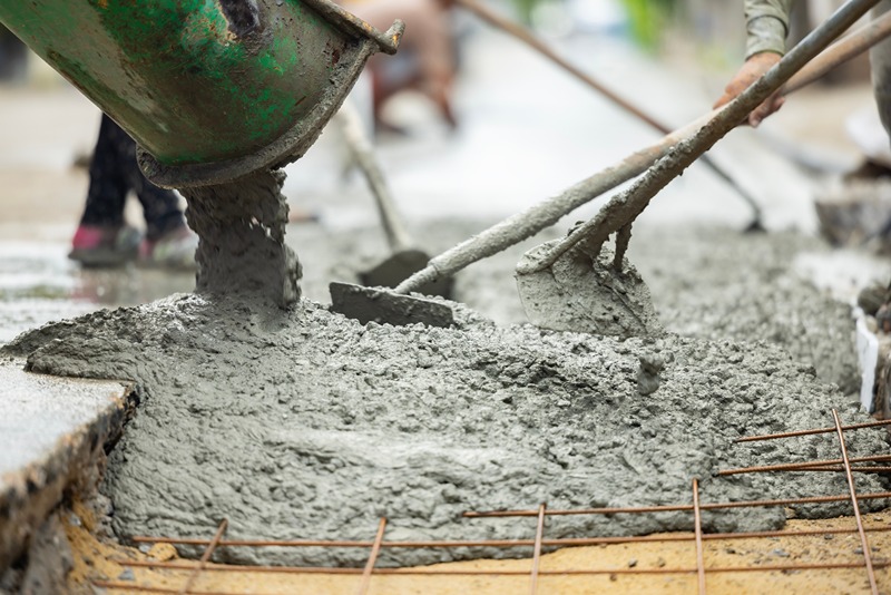 workers_pouring_concrete_mixture_on_a_construction_site_while_using_shovels_to_spread_it_evenly