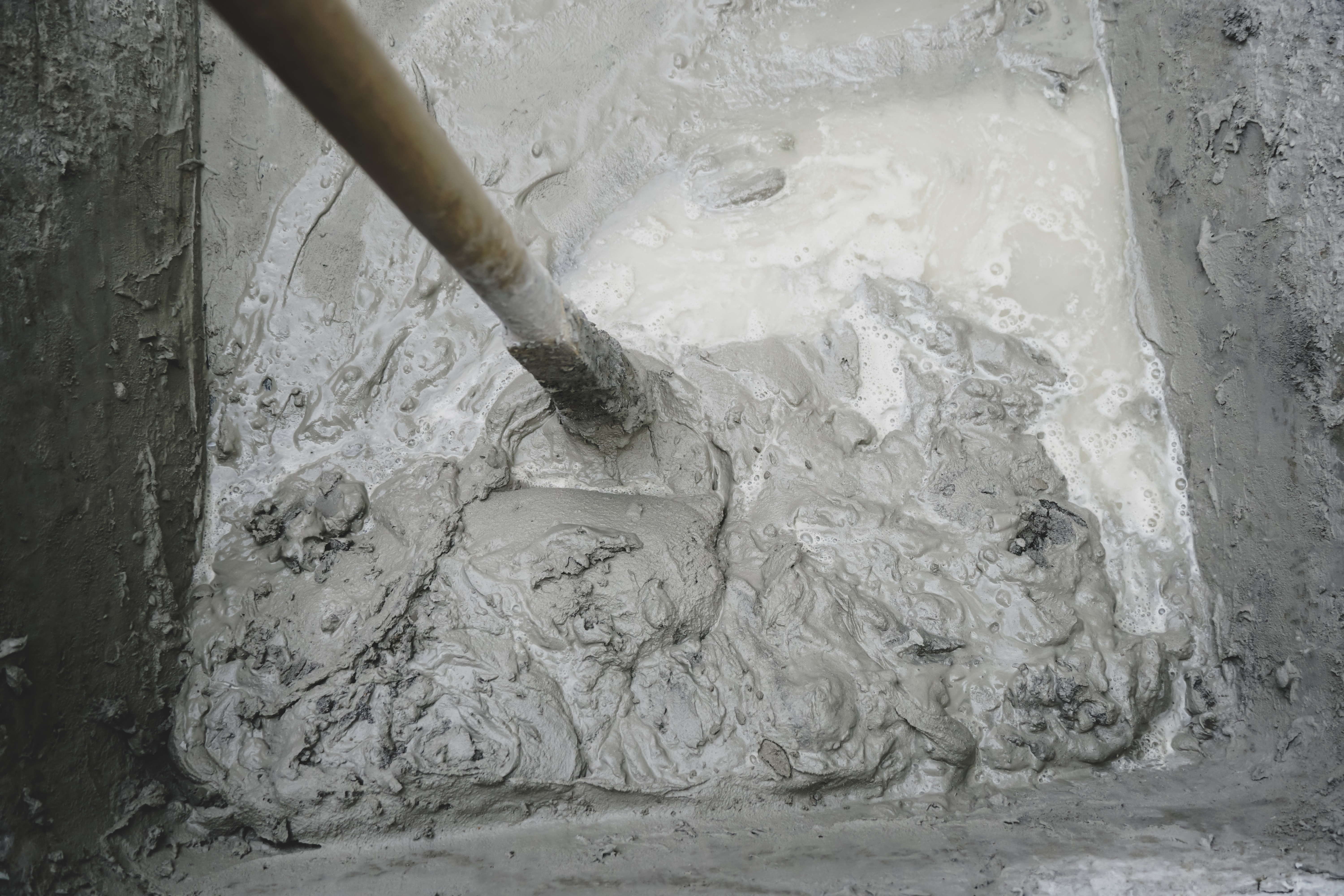 construction_worker_preparing_a_concrete_mix_on_the_ground_with_a_shovel