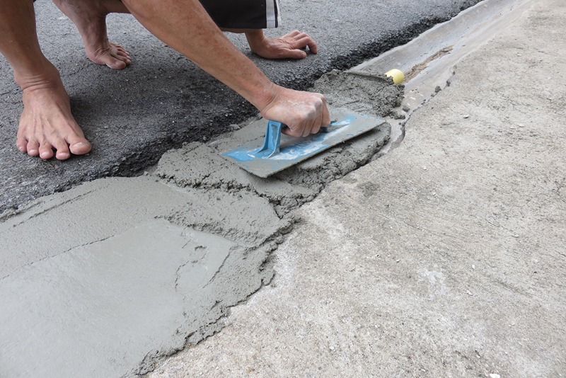 A_man_uses_the_plastic_trowel_to_make_the_smooth_surface_of_concrete_(Mixing_of_Portland_cement,_sand,_and_water)