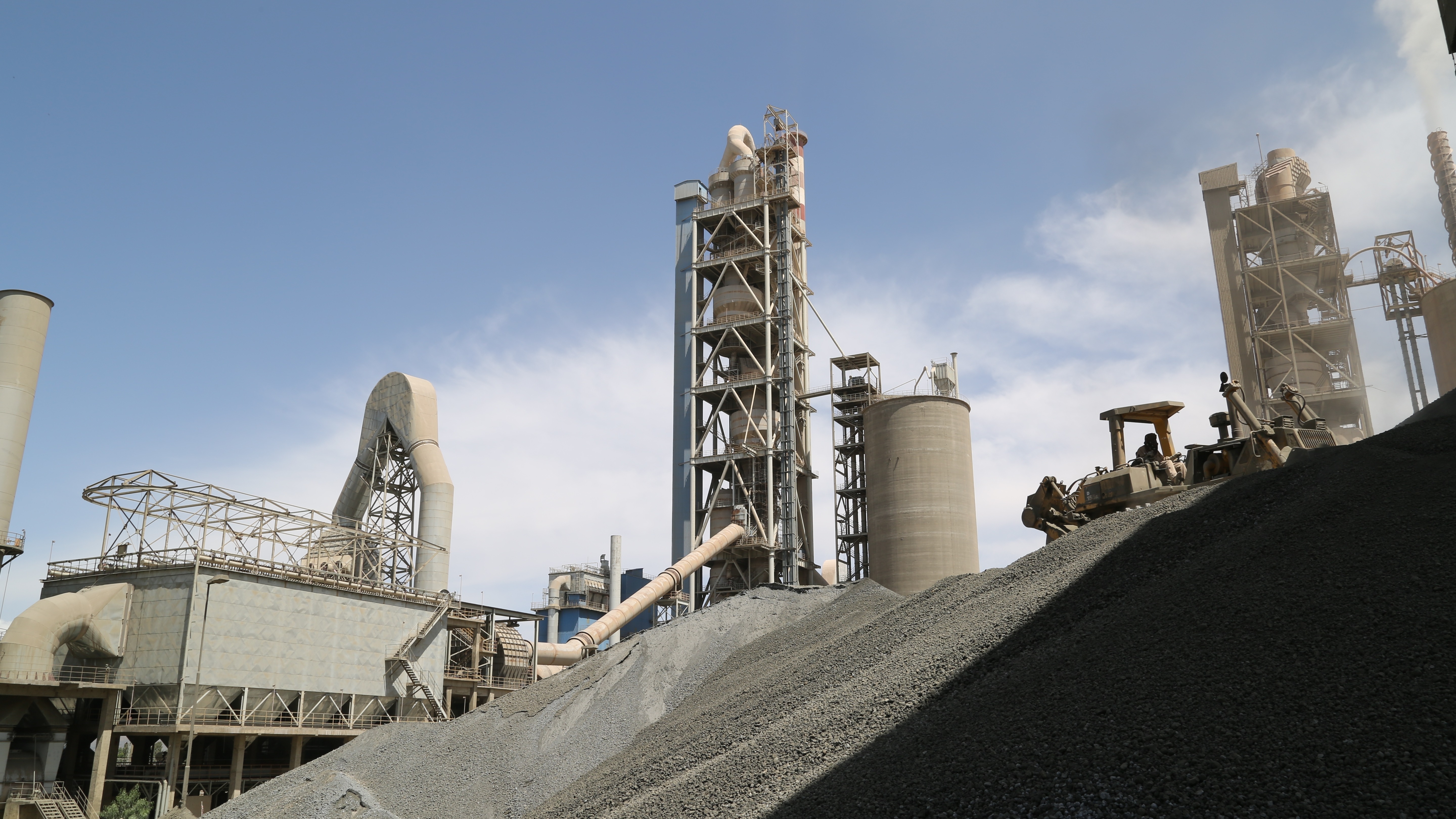 Industrial_cement_storage_silos_with_piles_of_aggregates_in_the_foreground.