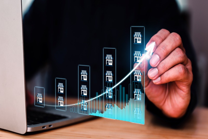 hand_drawing_growth_curve_over_graph_with_store_icons_symbolising_business_expansion