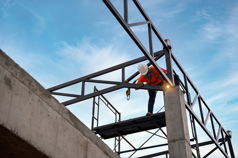 worker_installing_steel_trusses_for_PEB_roof_construction_with_blue_sky_background