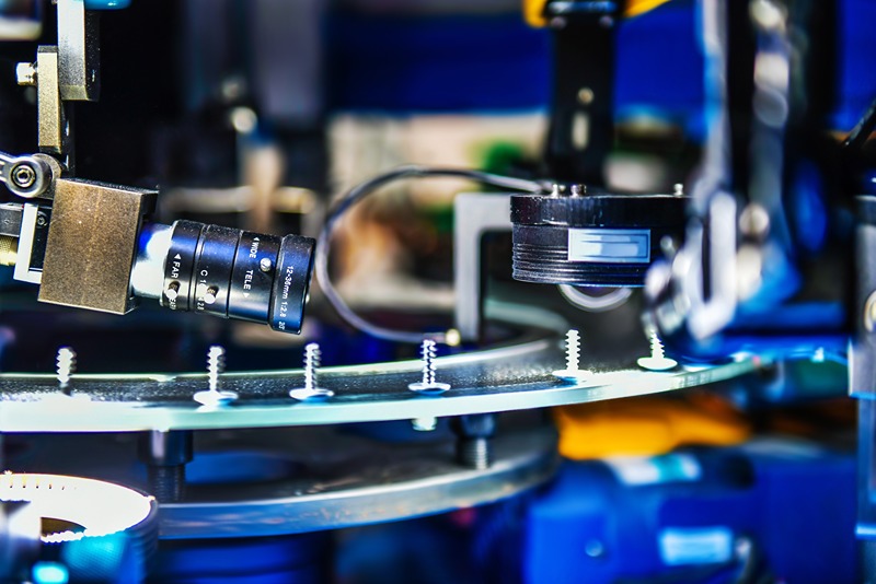 Close-up_of_an_industrial_camera_inspecting_steel_fasteners_on_a_manufacturing_assembly_line.