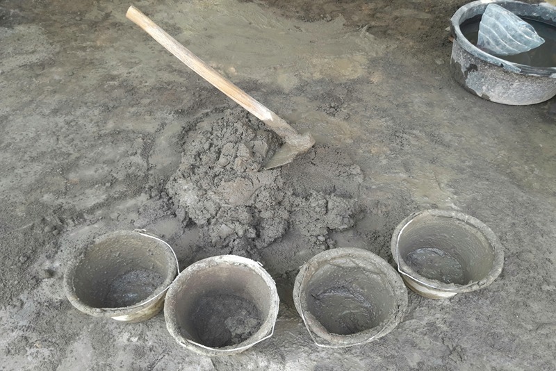 multiple_buckets_filled_with_freshly_mixed_concrete_arranged_on_a_cement_floor_with_a_shovel