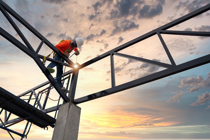 construction_worker_welding_steel_trusses_at_sunset_for_a_PEB_structure