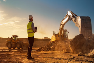 engineer_in_high_visibility_vest_on_construction_site_with_excavators_in_background