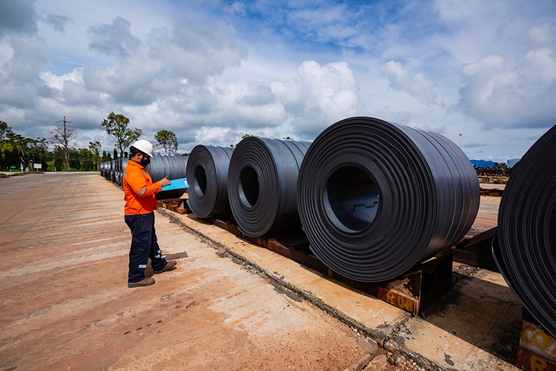 industrial_worker_inspecting_hot_rolled_steel_coils_outdoors