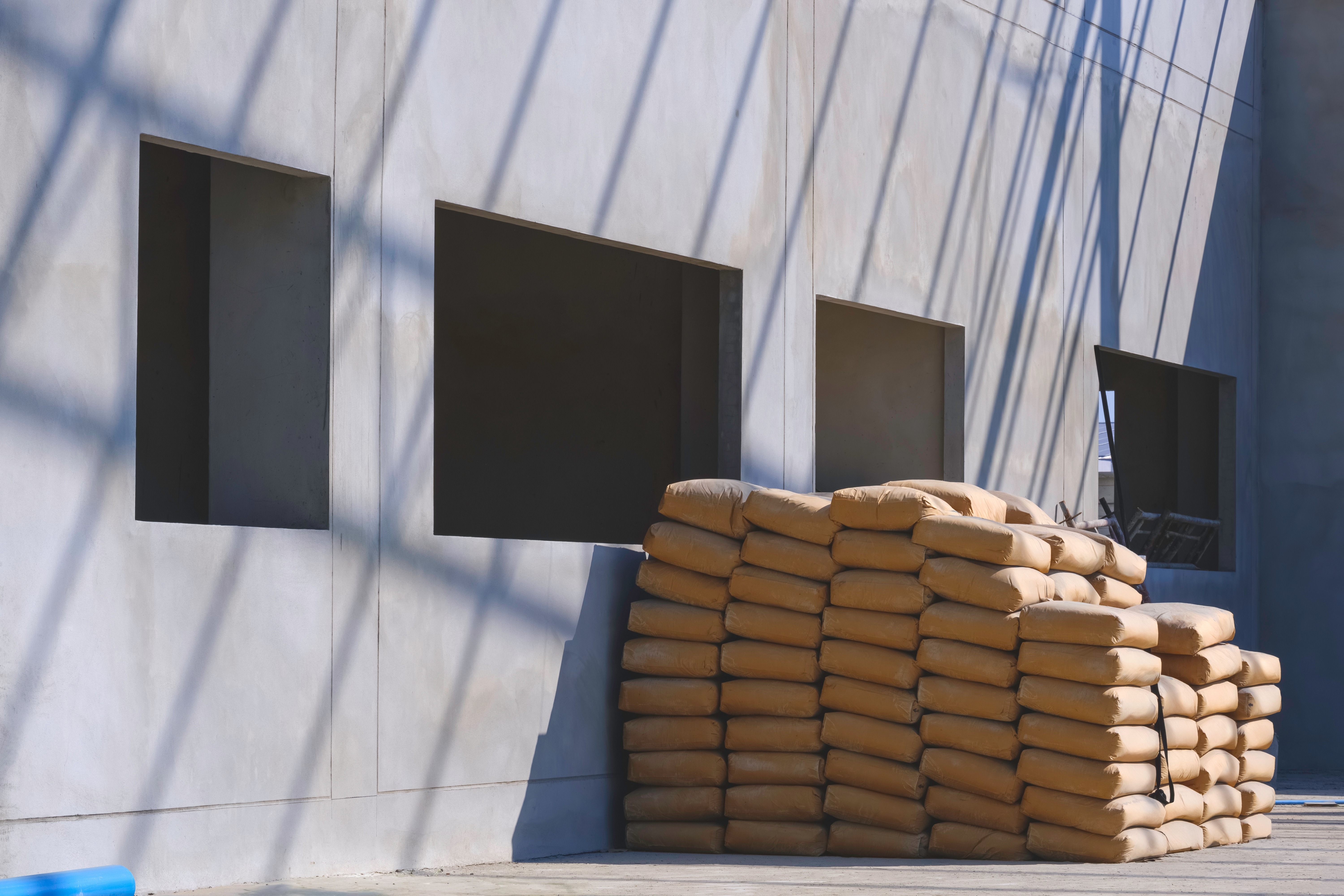 Stacks_of_cement_bags_outside_a_construction_building_under_sunlight.