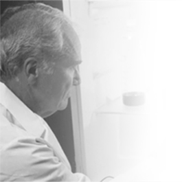 Oudere man kijkt uit een raam. Zwart/wit foto.