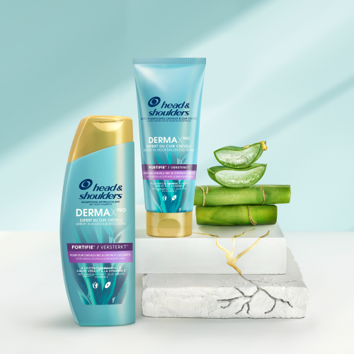 Derma X Pro Versterkt Head & Shoulders shampoo en conditioner flessen, naast stukjes aloe vera en bamboo