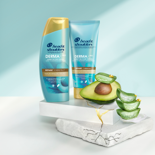 Derma X Pro Herstelt Head & Shoulders shampoo, conditioner en hoofdhuidbalsem flessen, naast stukjes aloe vera en avocado