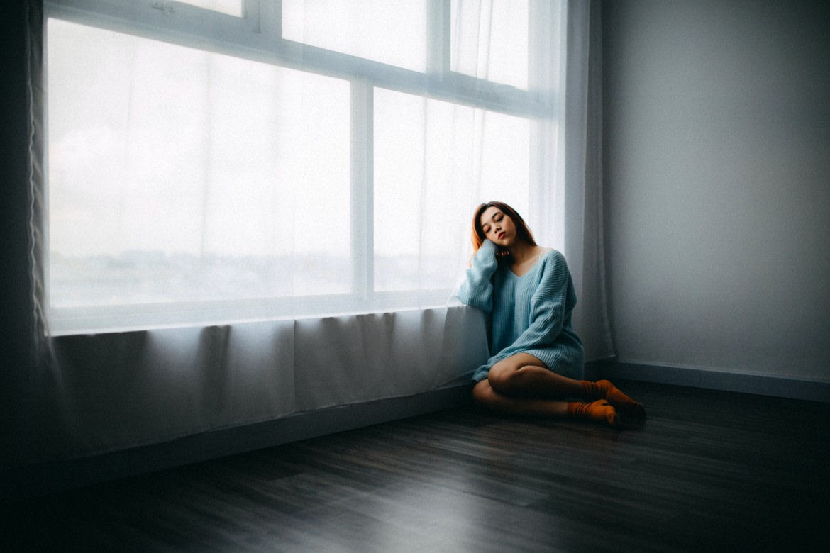 Woman sitting on the floor near a window