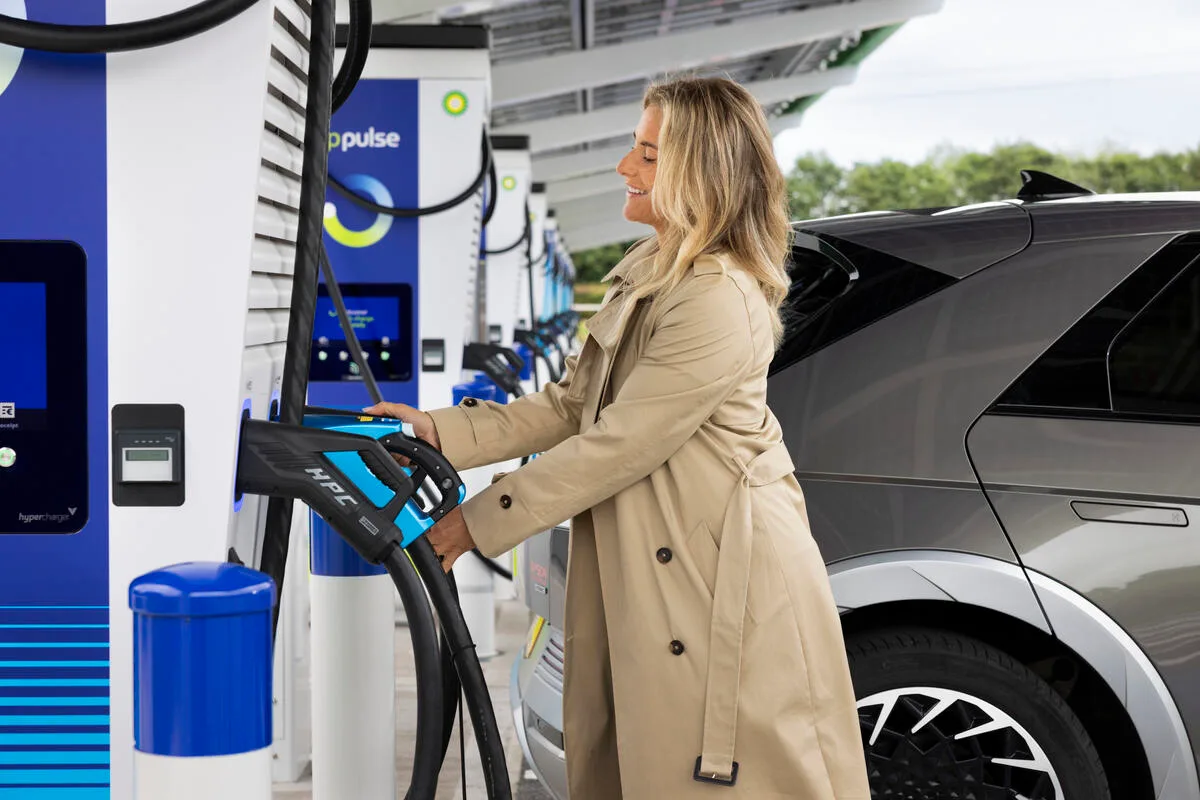 A woman charging her electric vehicle at a bp pulse charging station.